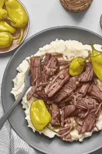 Juicy Mississippi Roast piled high over a mountain of steamy mashed potatoes, topped with tangy pepperoncini peppers.